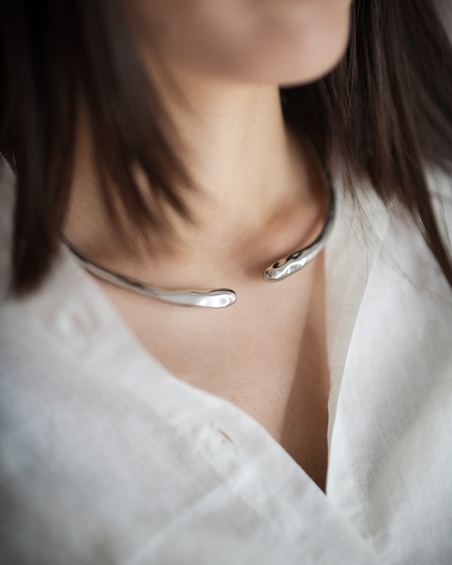 گردنبند نقرهای مینیمال روی گردن زن با پیراهن سفید
